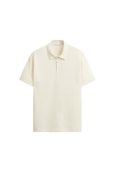 White short-sleeved polo shirt with a classic collar and three buttons on the front. White background. Visible label inside the collar.