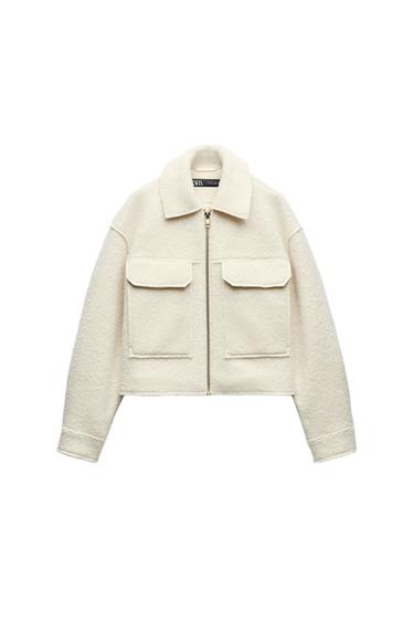 Front view of a white jacket with zip fastening and front flap pockets.