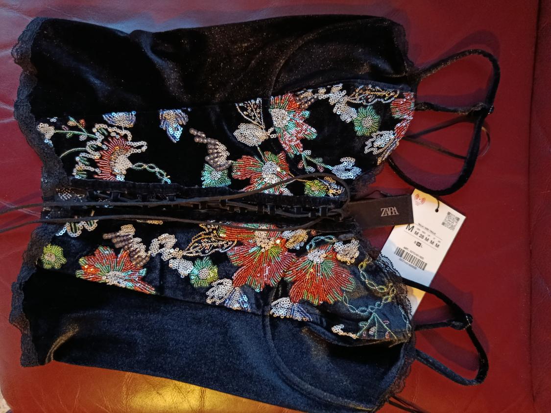Black top with thin straps and colourful sequin floral embroidery. Visible label with text "ZARA" and size "M".
