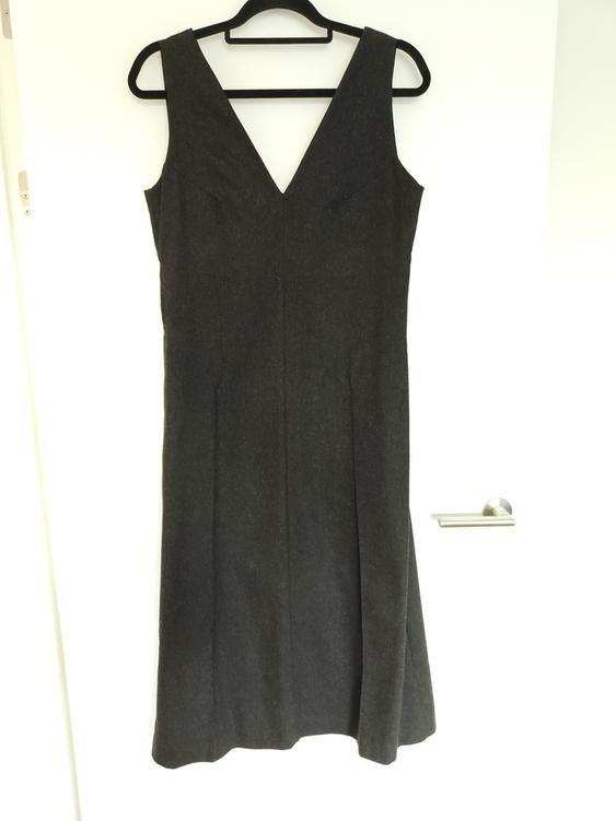 Sleeveless black dress with a V-neckline, hanging on a black hanger over a white door.