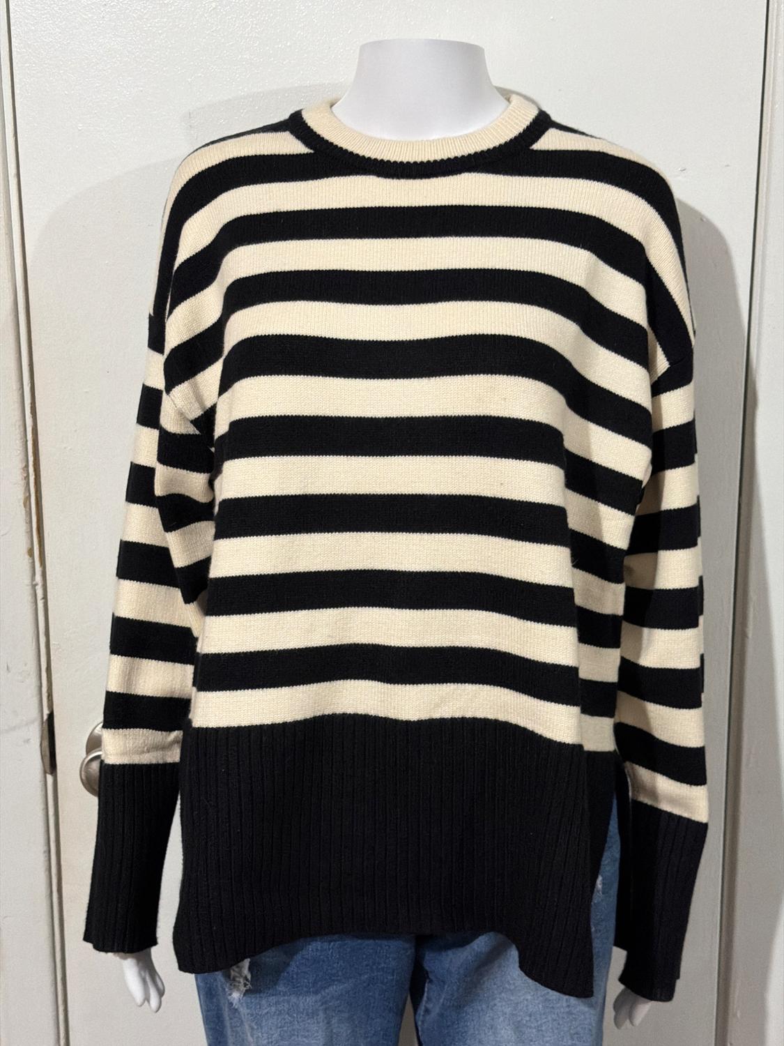 Mannequin in a black and white horizontal striped jumper, paired with blue jeans. White wall background.