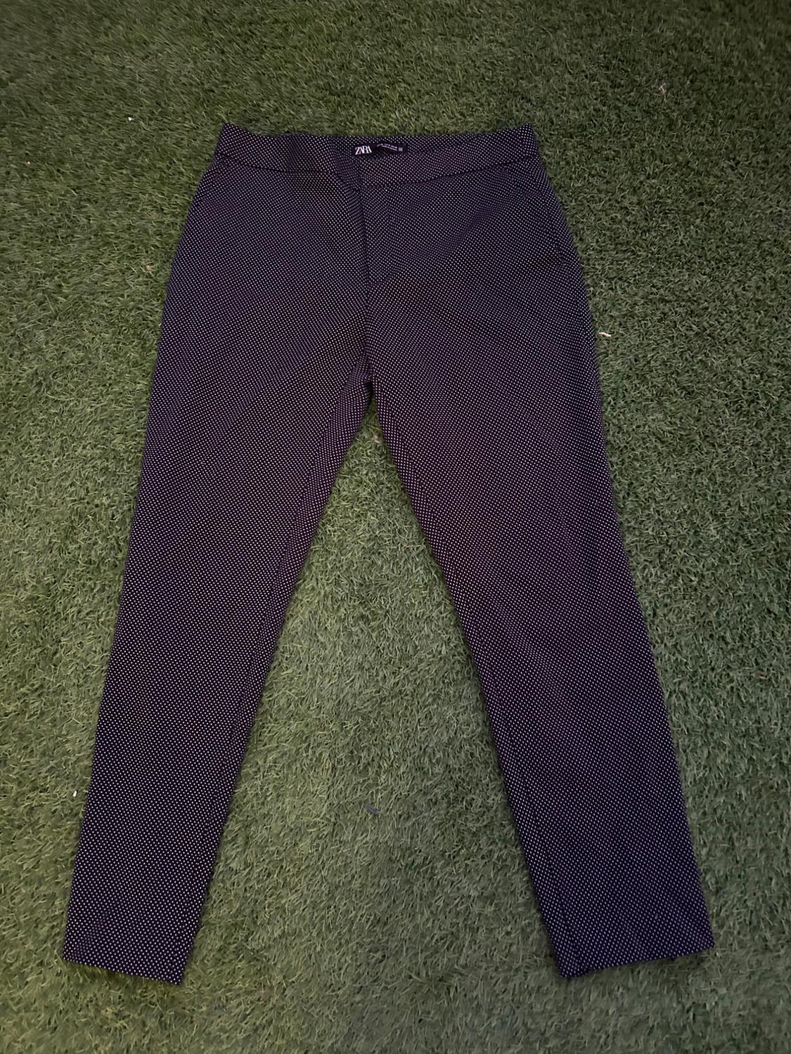 Dark trousers with a small white polka dot print on green grass. Label visible at the waist.