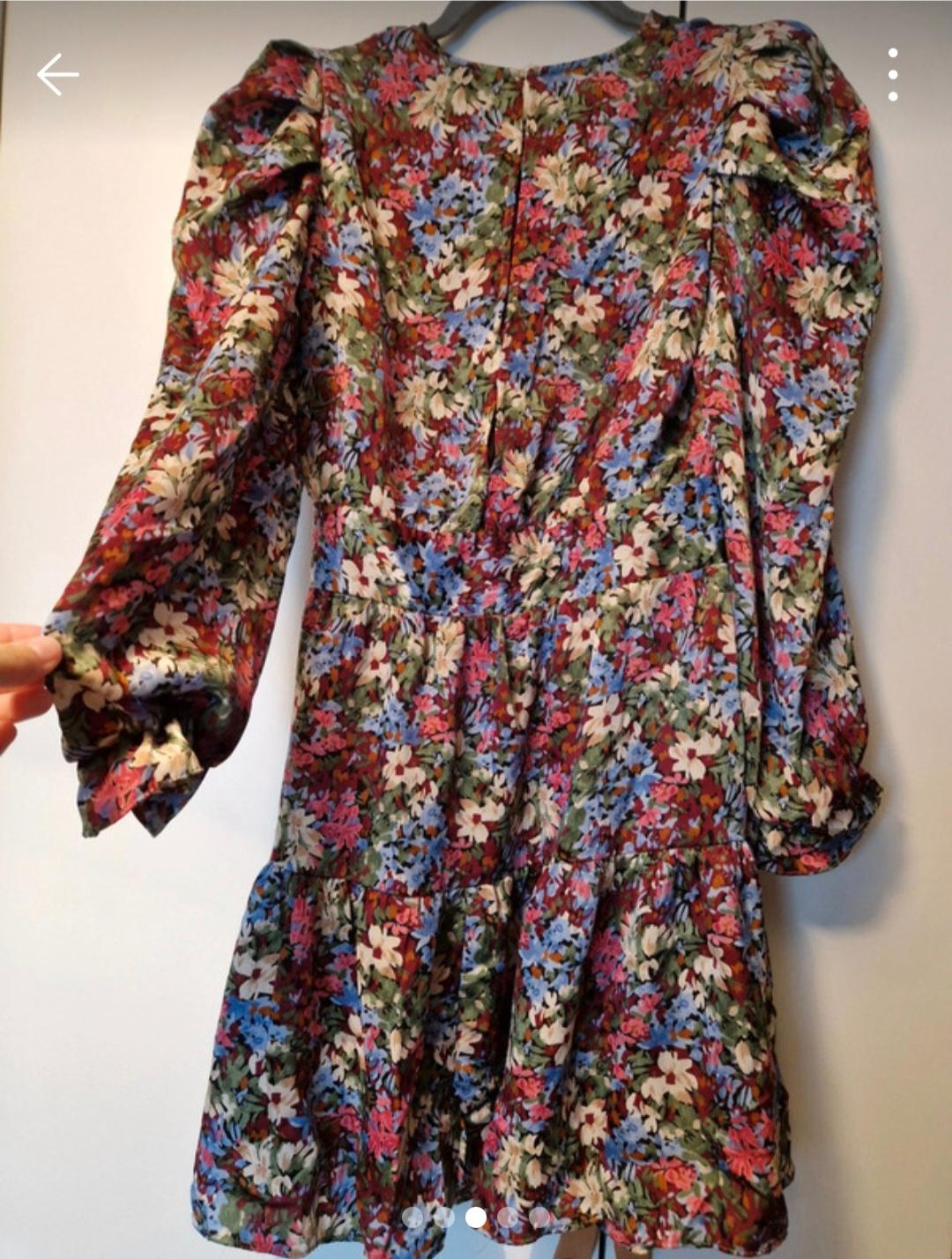 Long-sleeved floral dress with a red, blue, and green flower print, hanging on a hanger against a white background.