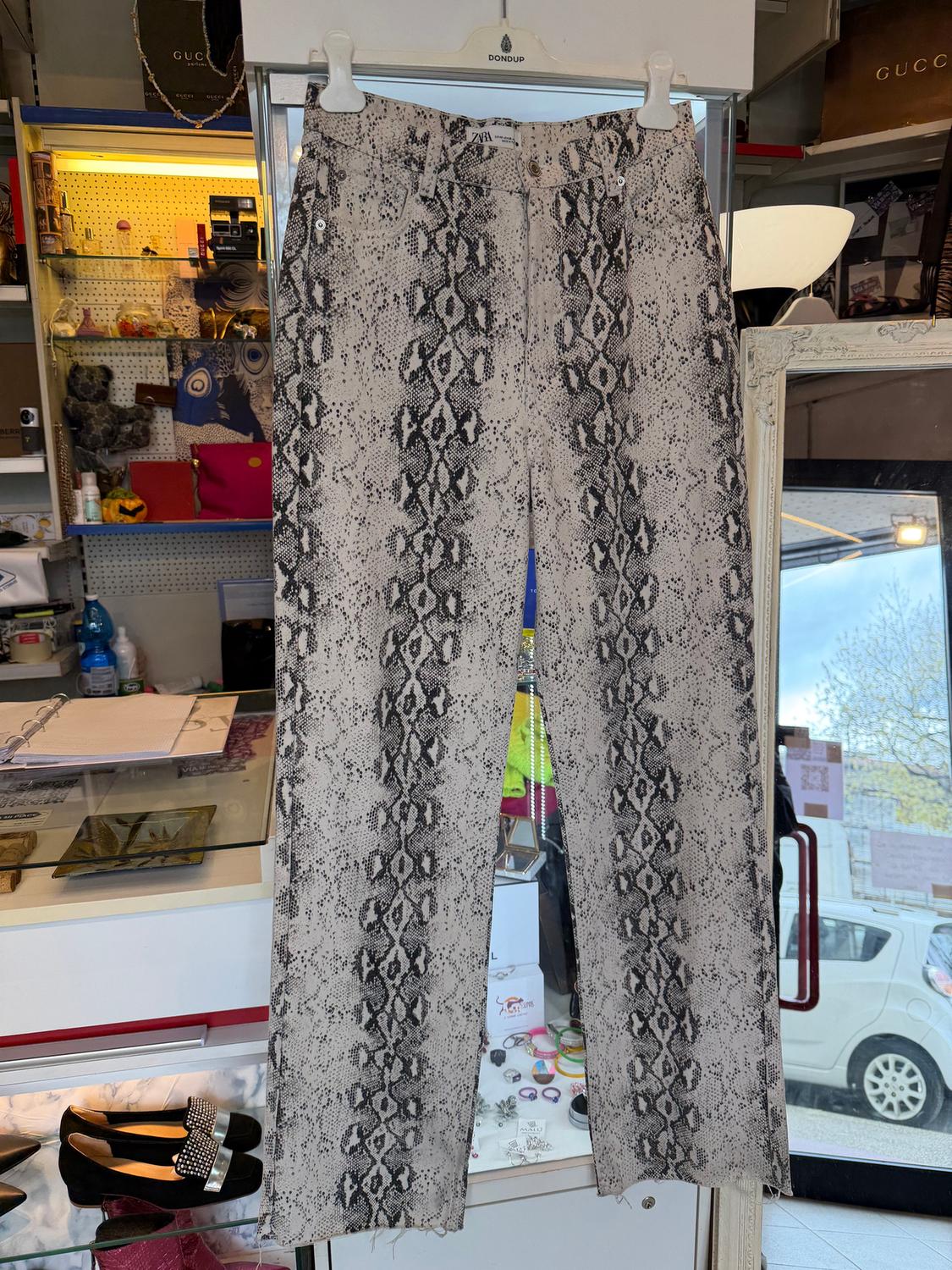 Snake print trousers hanging in a shop, surrounded by accessories and shoes on display.