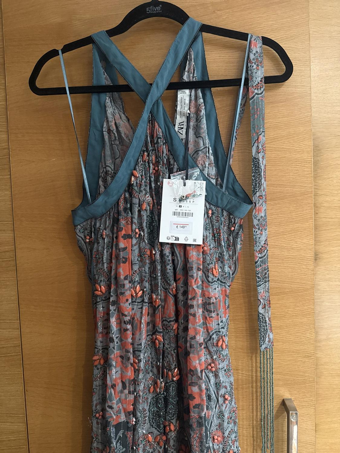 Grey and orange patterned dress with beadwork hanging on a wooden door. Text: 5five ZARA S € 149.00.