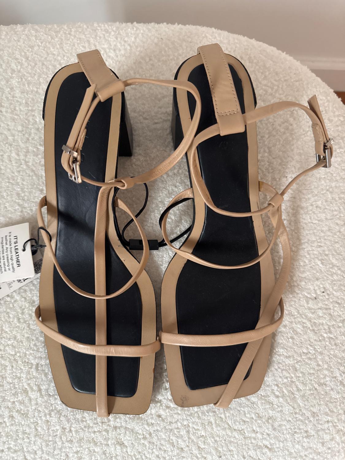 Top view of beige heeled sandals with thin straps and silver buckles.