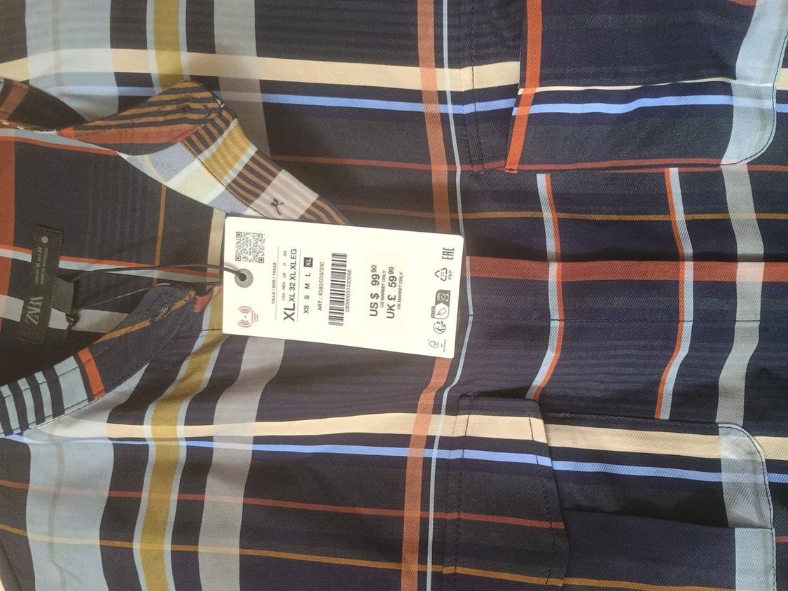 Multicoloured checked shirt with a price tag of $39.90. Available sizes: XS to XL. Barcode and QR visible.