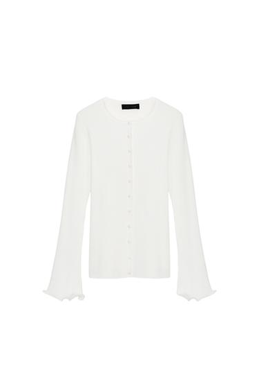 Front view of a white knit jacket with a round neck, long sleeves, and a wavy finish. Front button closure.