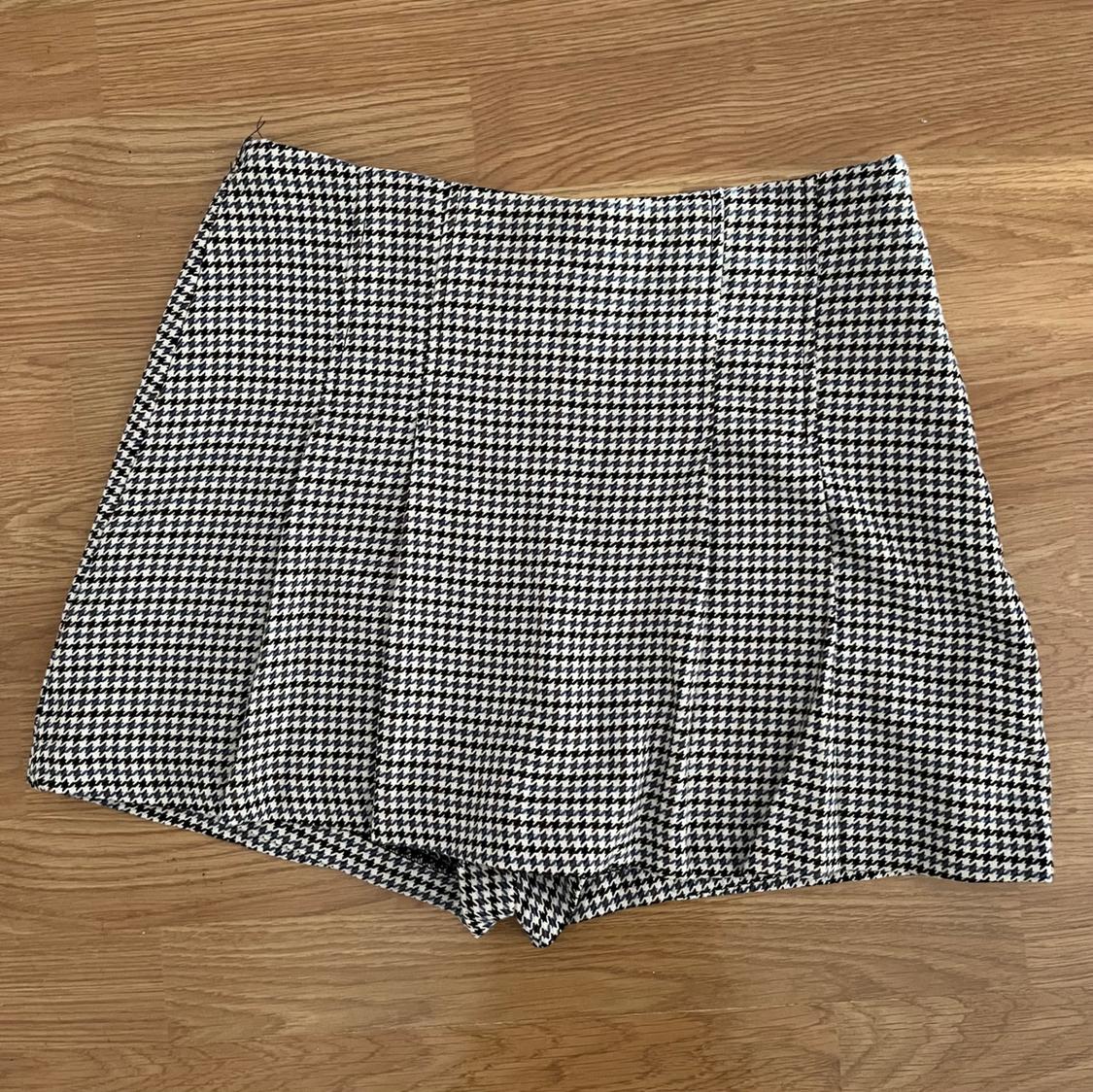 Short houndstooth skirt in black and white on a light wooden floor.