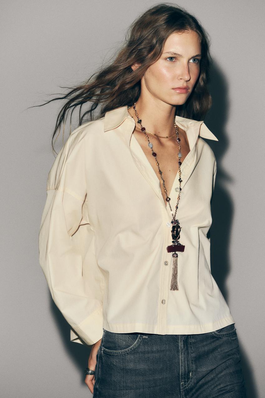 Halbnahe Aufnahme eines hellgelben Hemdes mit Hemdkragen, V-Ausschnitt und langen Ärmeln. Knopfleiste vorne.