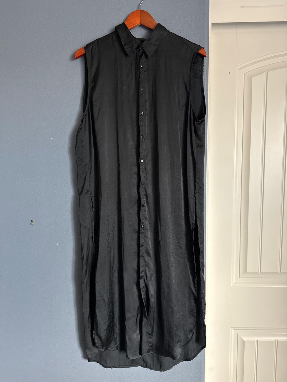 Front view of a black sleeveless dress with a button front and classic collar.