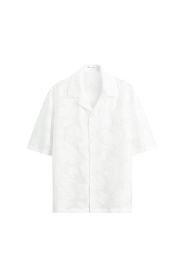 White short-sleeve textured shirt with an open collar and front buttons, on a white background.