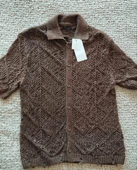 Brown knitted argyle cardigan with a classic collar and buttons down the front, on a light-coloured rug. White tag hanging.