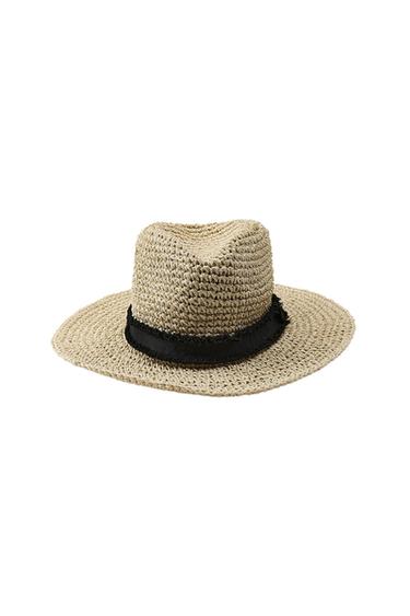 Natural-coloured braided straw hat with a wide brim and a frayed black ribbon at the base of the crown, on a white background.
