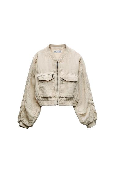 Front view of a beige short jacket with front pockets and zip fastening.