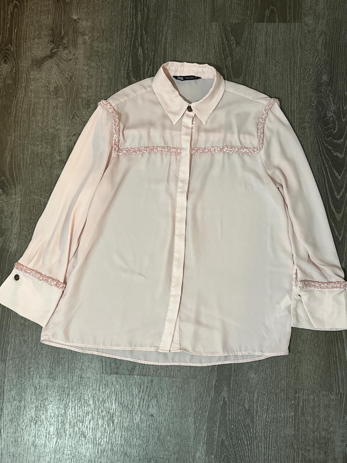 Light pink shirt with lace details on the shoulders and sleeves, on a dark gray wooden background.