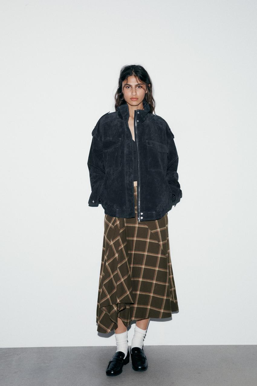 Black jacket set with front pockets and brown plaid midi skirt.