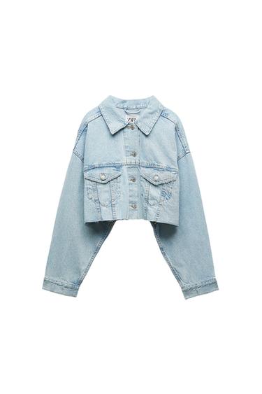 Light wash denim crop jacket with buttons and front pockets. Visible tag on the neck. White background.