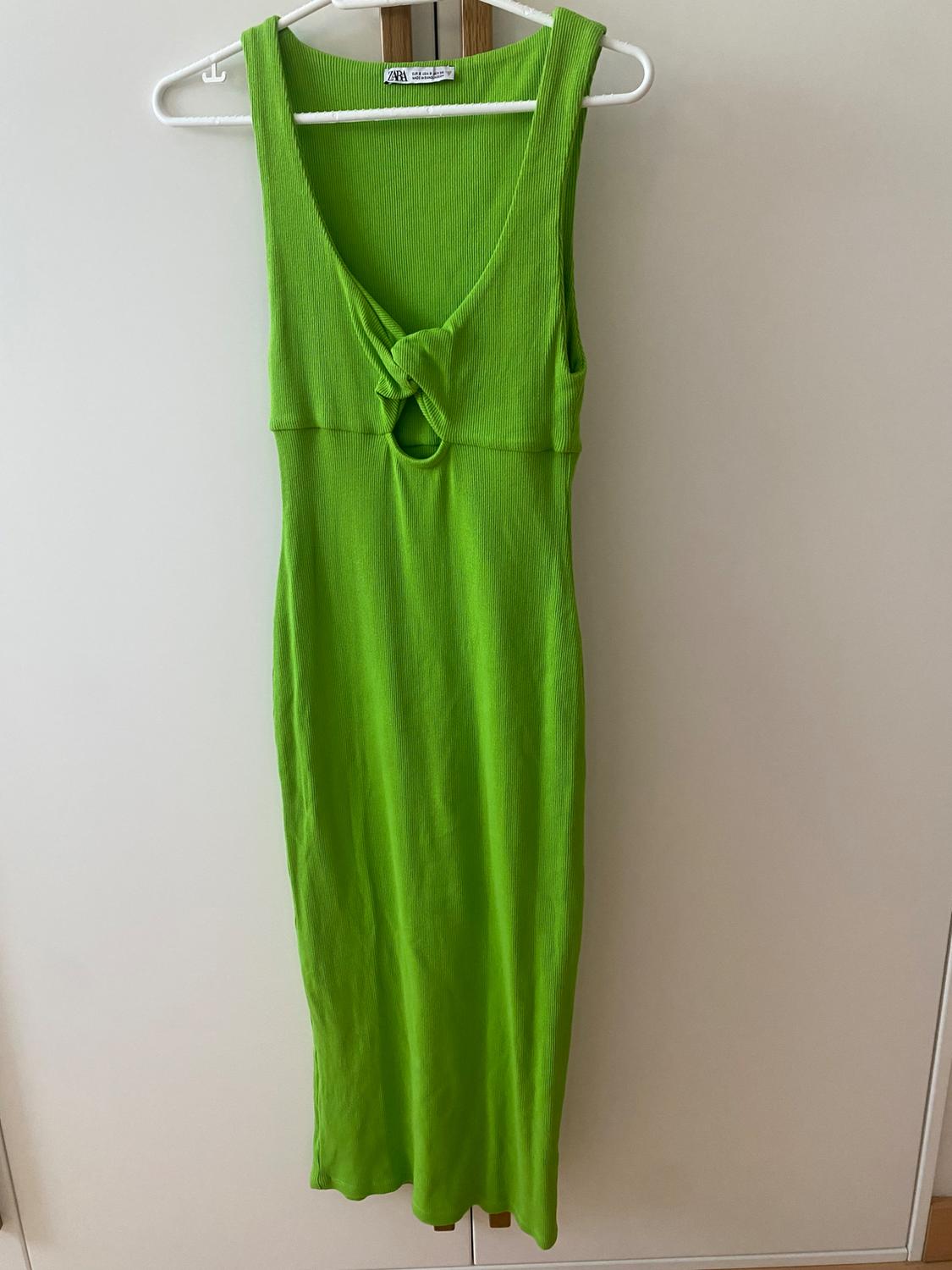 Lime green sleeveless maxi dress with a V-neck and front knot detail, hanging on a white hanger.