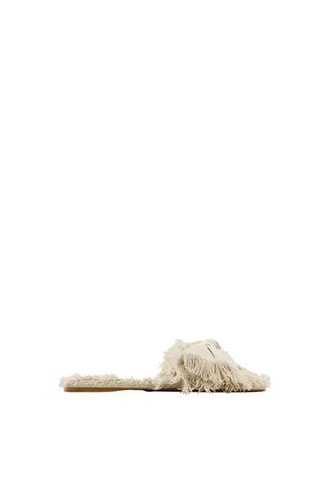 Side view of beige fringed sandal.
