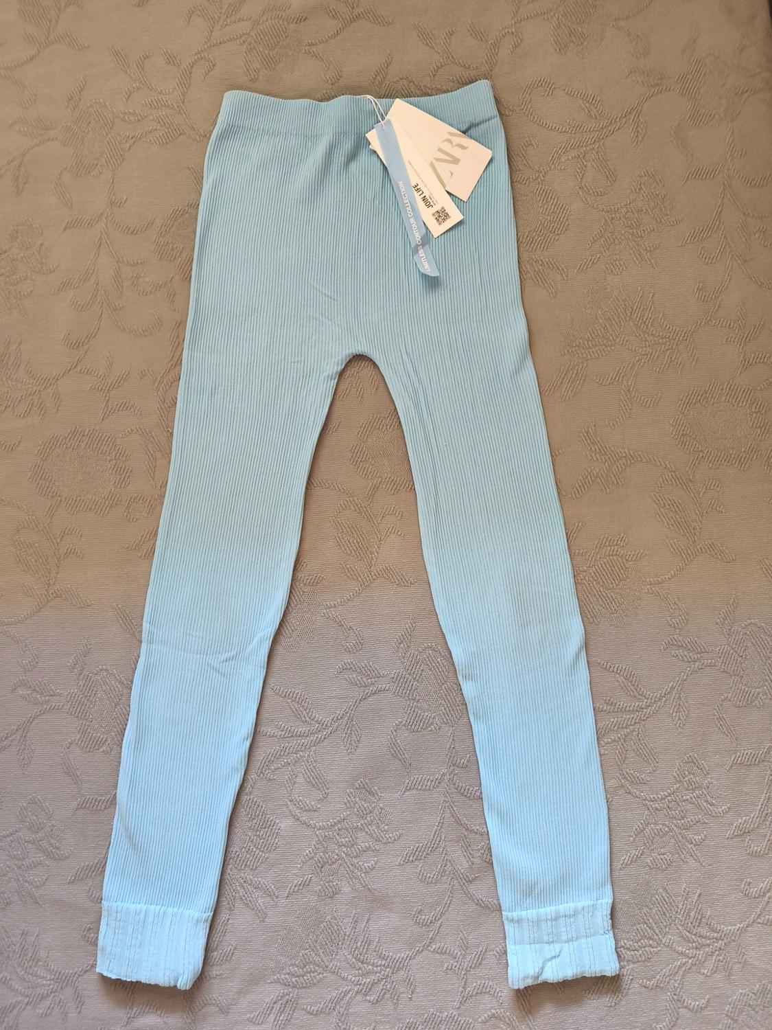 Light blue ribbed trousers on a patterned background. Labels with the text ZARA, JOIN LIFE, LIMITLESS CONTOUR COLLECTION.