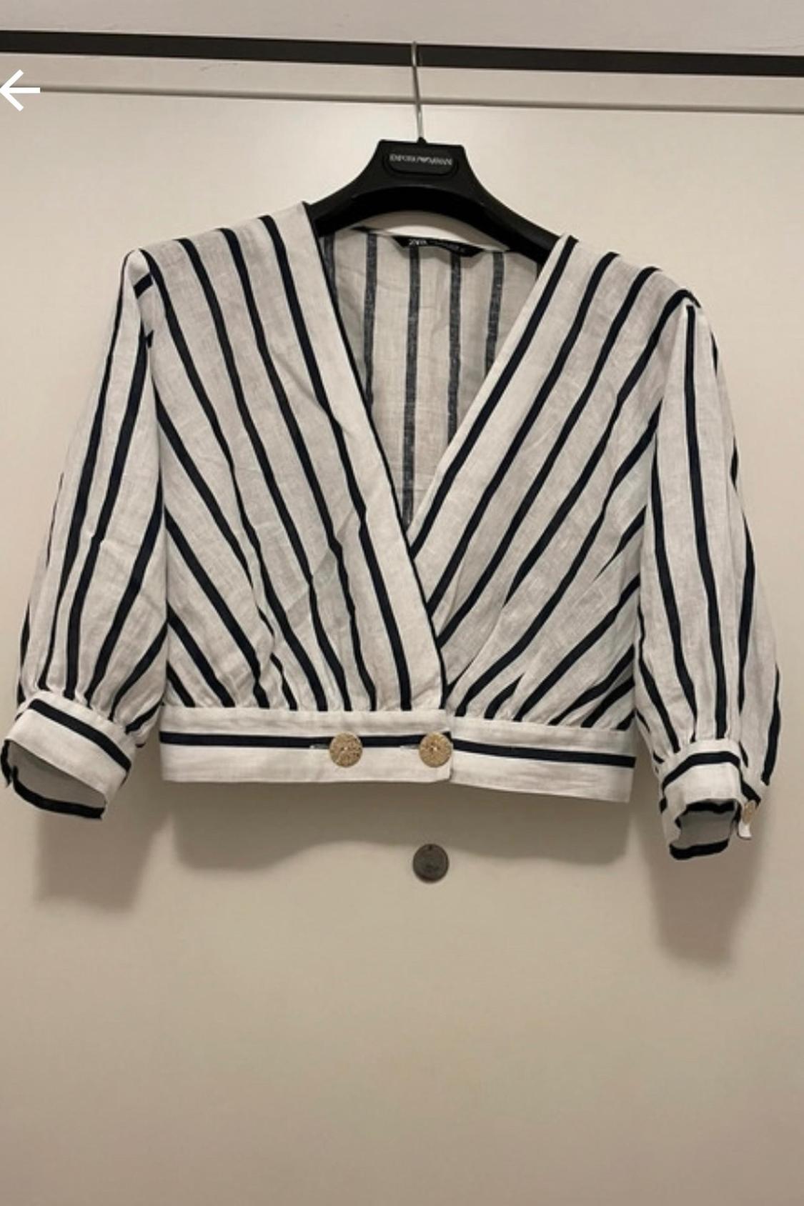 Front view of a black and white striped blouse with gold buttons and puff sleeves.