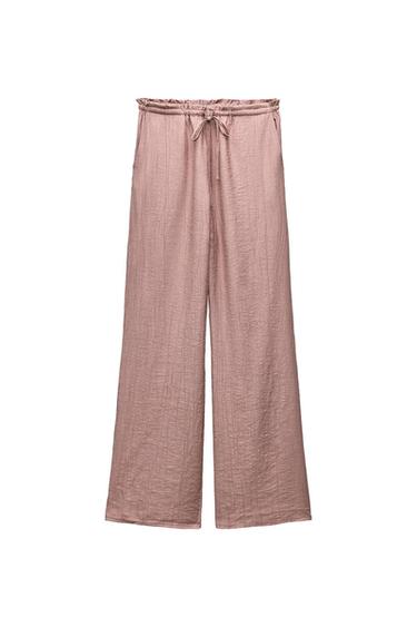 Wide-leg pink trousers in textured fabric with an elasticated waistband and adjustable drawstring, shown against a white background.