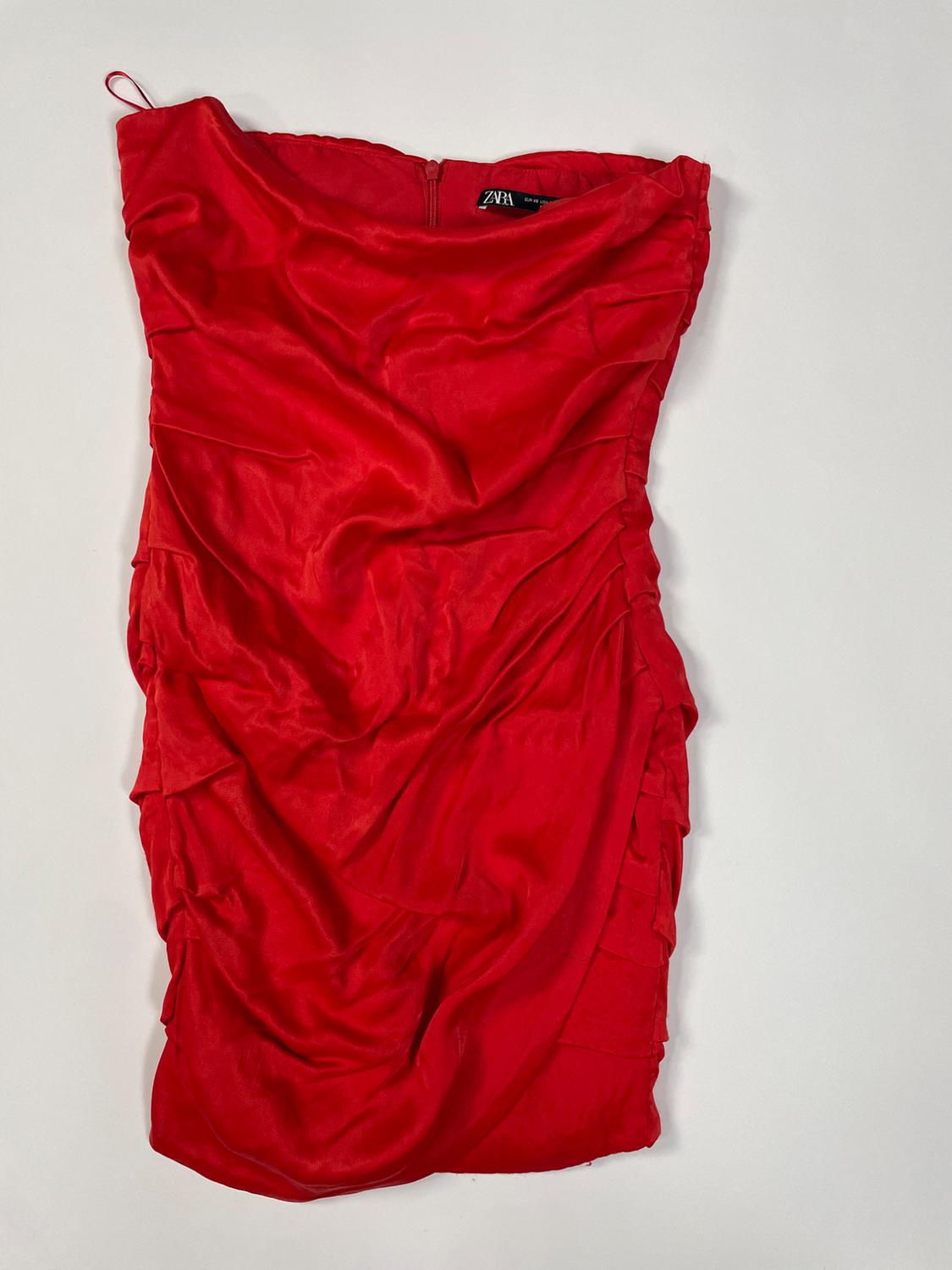 Red strapless short dress with gathered design on a white background. Interior label with ZARA text.