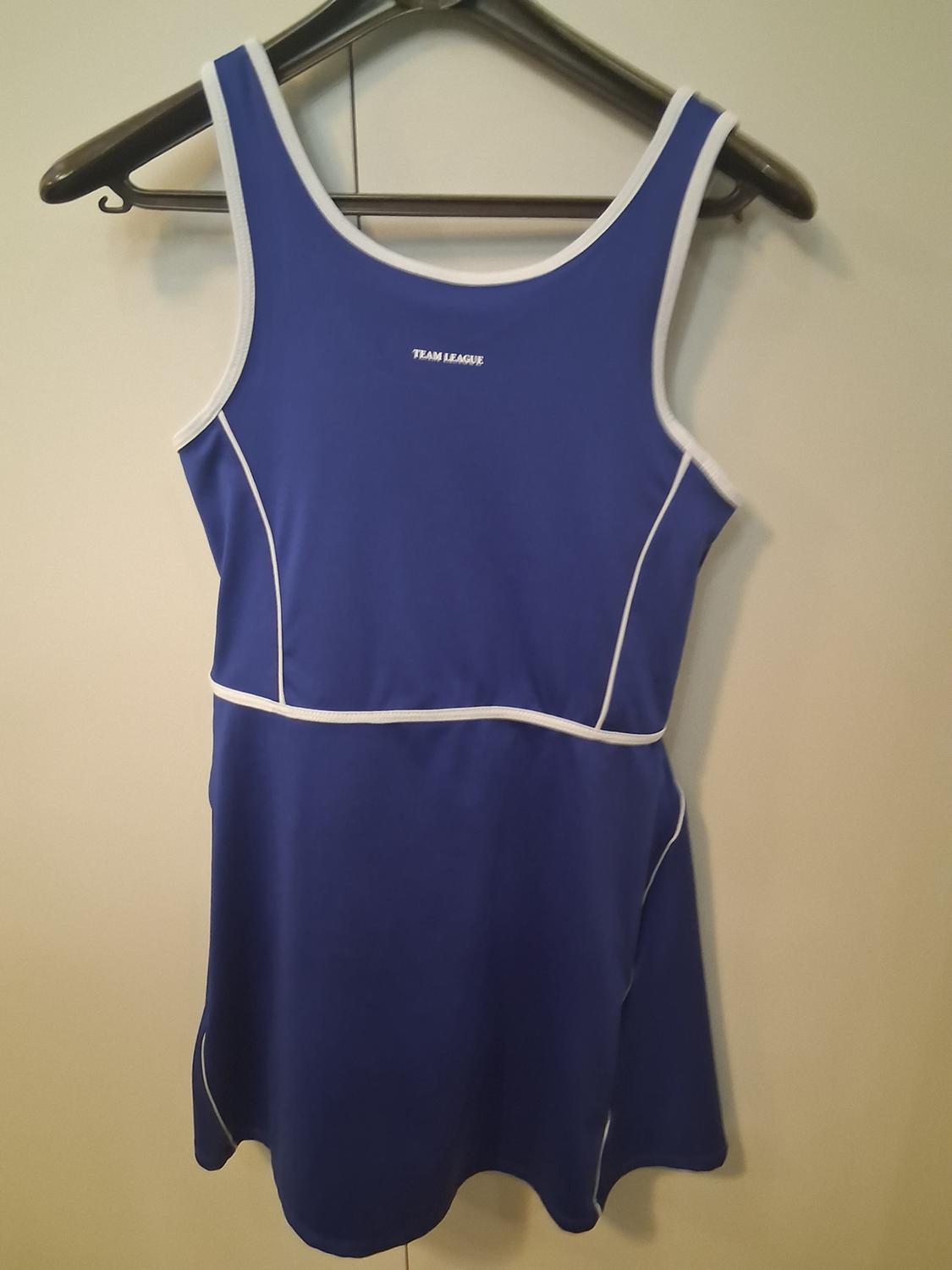 Blue sports dress with white trim, hanging on a black hanger. Visible text: "TEAM LEAGUE". Light background.