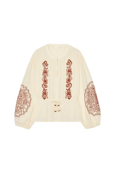 Front view of a beige blouse with brown embroidery on the chest and puff sleeves.