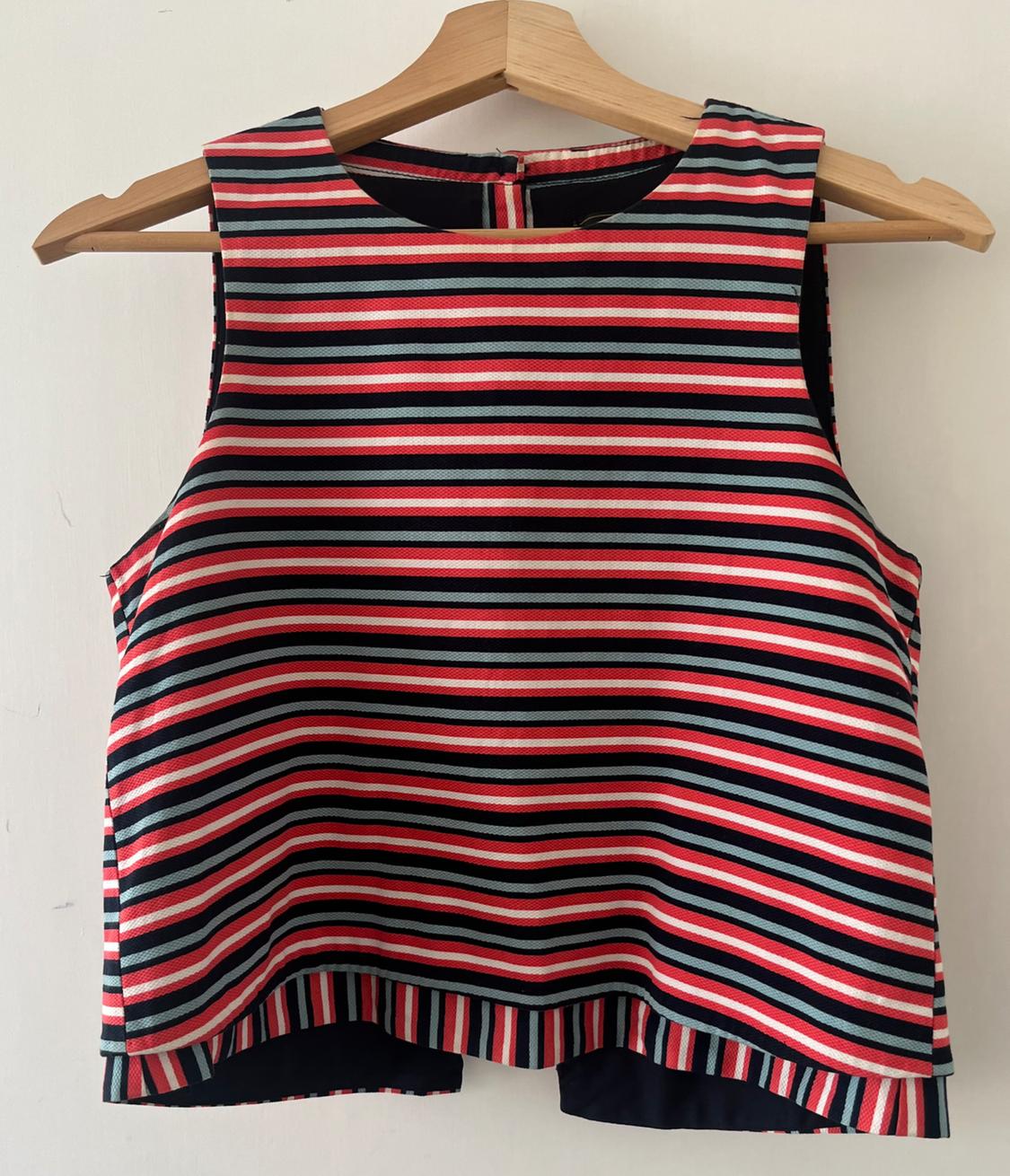Red, white, black and light blue horizontal striped sleeveless top, hanging on a wooden hanger against a white background.