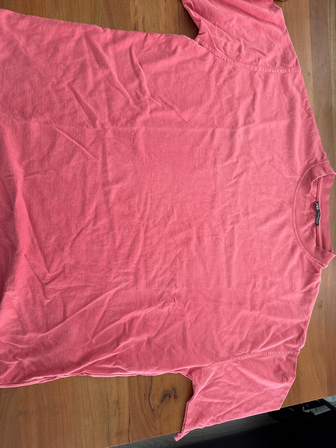 Wrinkled pink t-shirt on a wooden table.