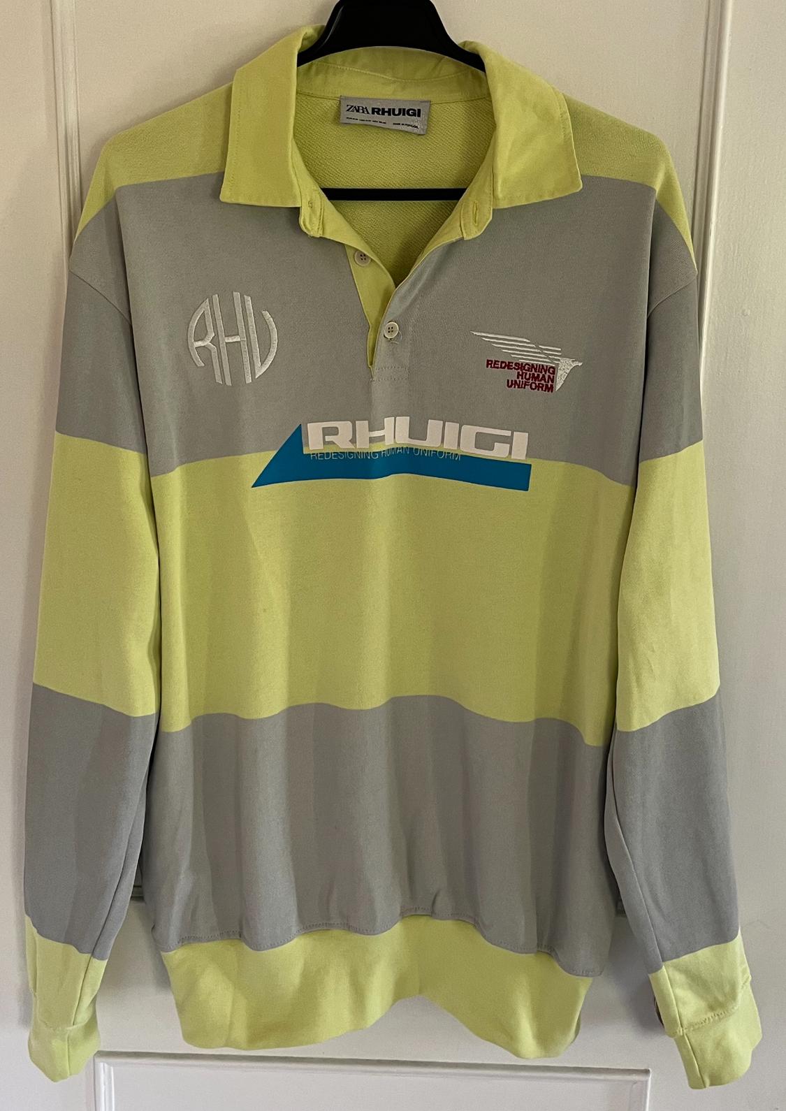 Front view of yellow and grey striped sweatshirt with polo neck. Visible text: 'RHUIGUI', 'REDESIGNING HUMAN UNIFORM'.