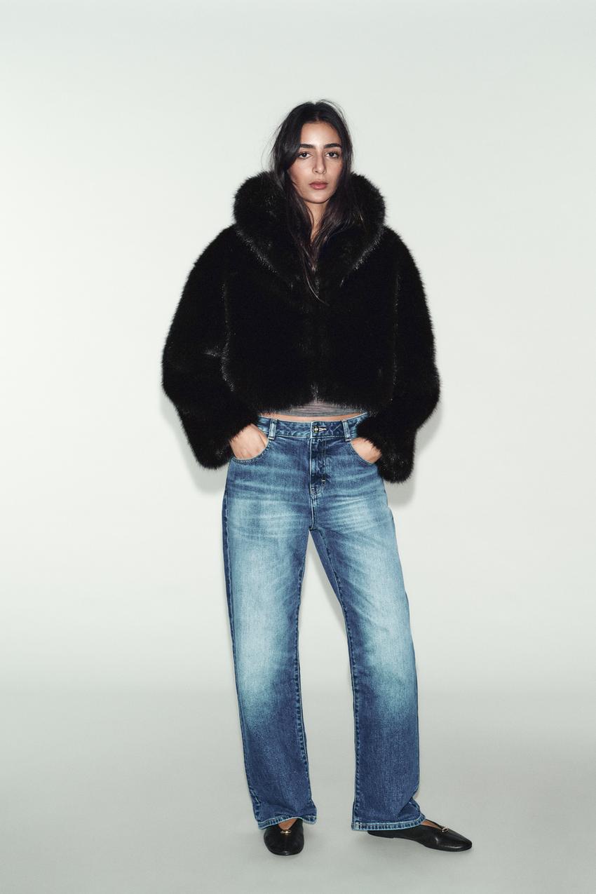Black faux fur cropped coat set with a lapel collar and long sleeves, straight blue jeans, and black shoes.