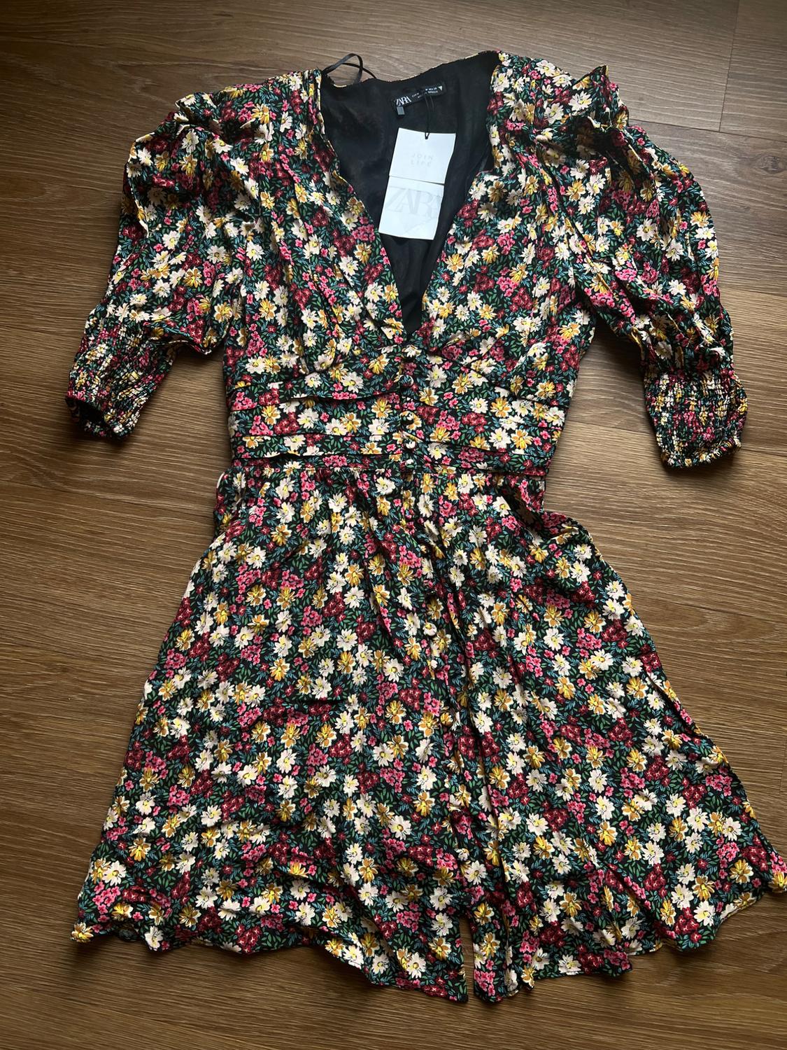 Front view of floral dress with puffed sleeves and V-neck. Red, white, and yellow floral print.