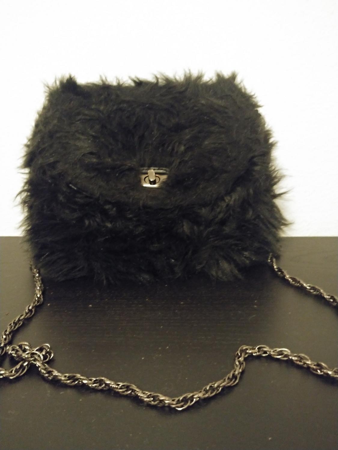 Front view of a black furry bag with a chain and metal clasp.