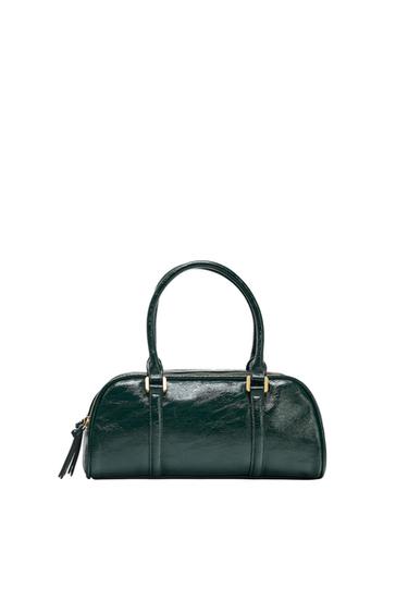 Dark green handbag with a glossy finish. It has two short handles, a zip fastening with a tassel and gold details against a white background.