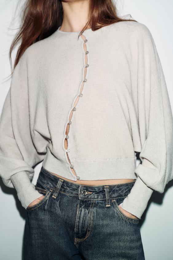 St�edn� z�b�r kamenn� bundy s kulat�m v�st�ihem a dlouh�mi ruk�vy, k��ov�m zap�n�n�m na knofl�ky vp�edu, v kombinaci s tmav�mi d��ny.