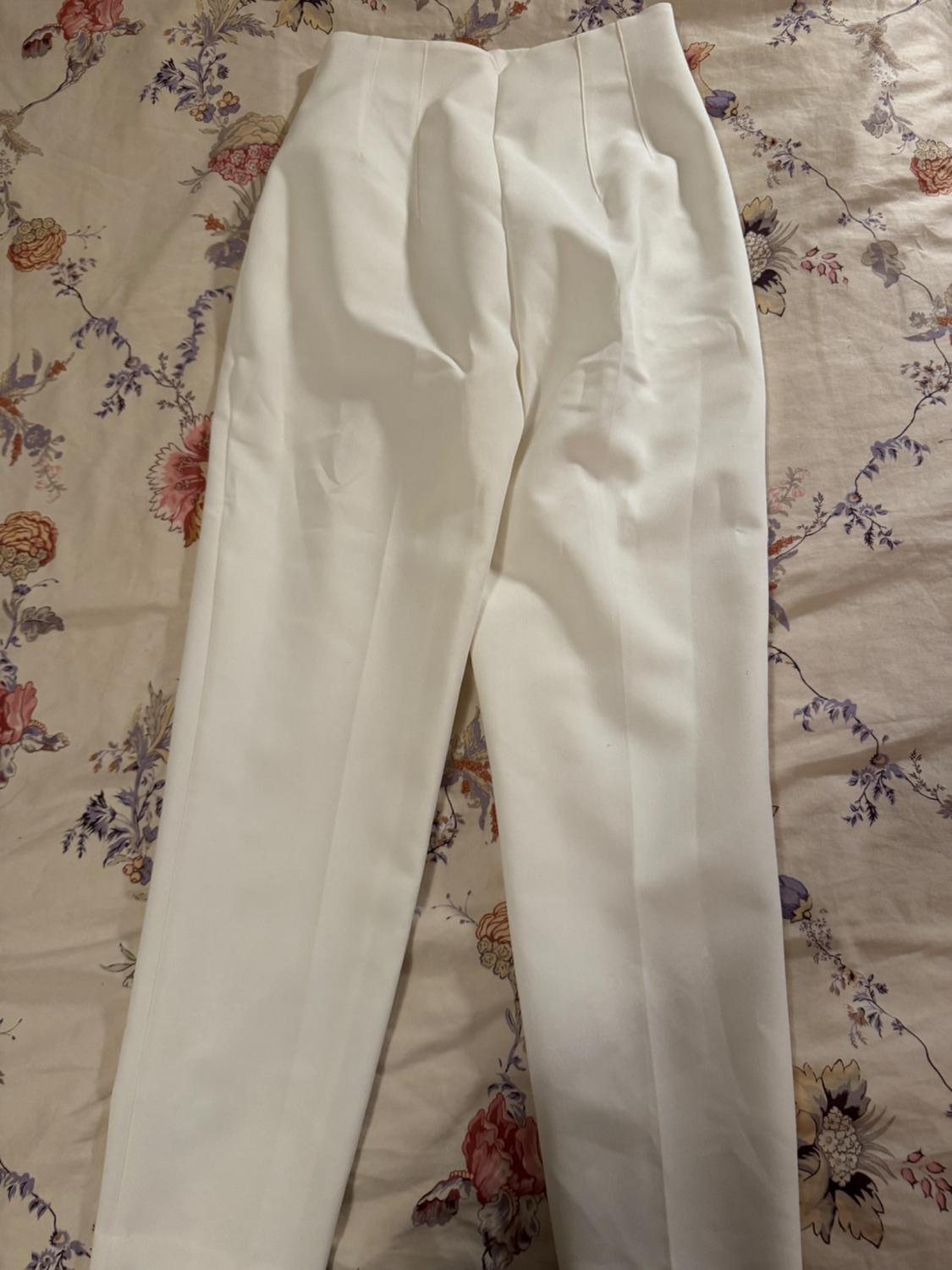 White dress pants on a floral print bedspread in pastel shades.