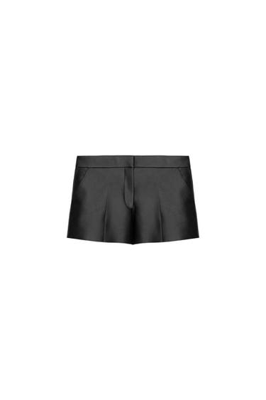 Black satin shorts with pleats, wide waistband and front fastening, on a white background.