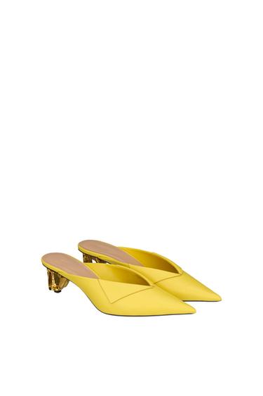Yellow slingback heels with a pointed toe, a fold on the vamp, and a textured gold heel on a white background.