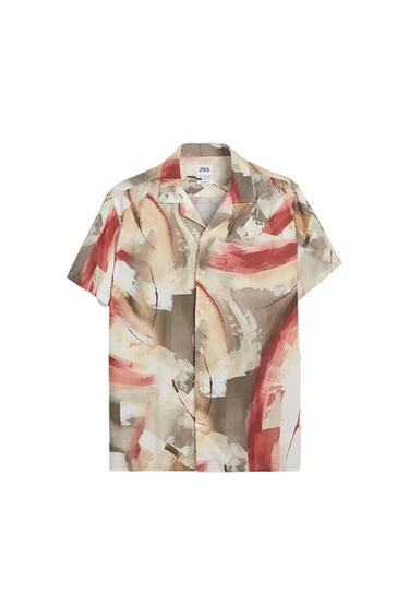 Short-sleeved shirt with an abstract print in beige, brown, and red tones. Open collar and front buttons. Visible label on the inside.