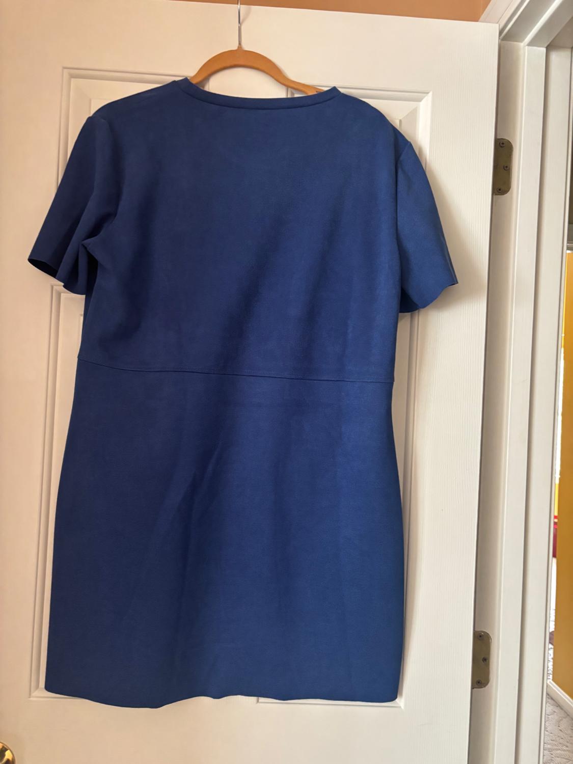 Short-sleeved blue dress hanging on a wooden hanger over a white door.