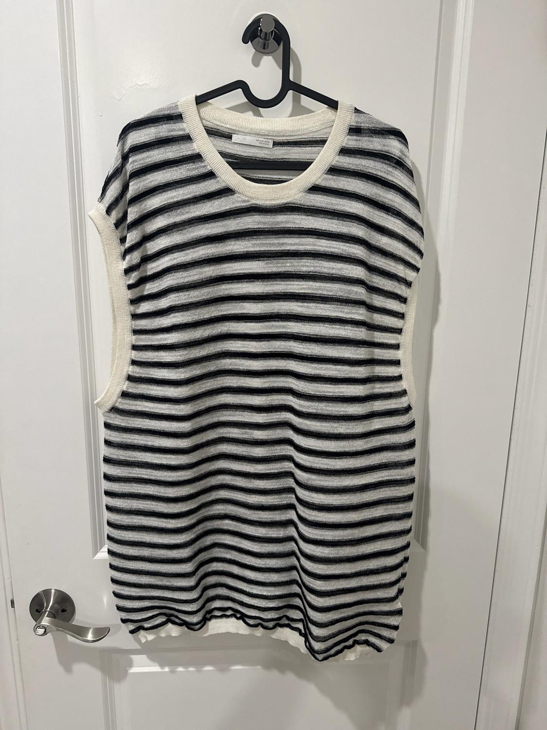 Sleeveless knit top with horizontal black and white stripes, a crew neck, and white trim, hanging on a white door.