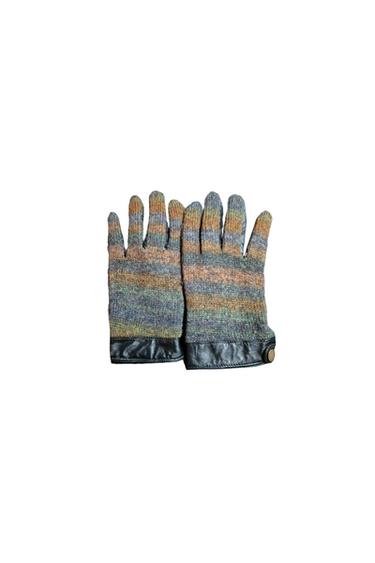 Multicoloured wool gloves with black leather cuffs and button, on a white background.