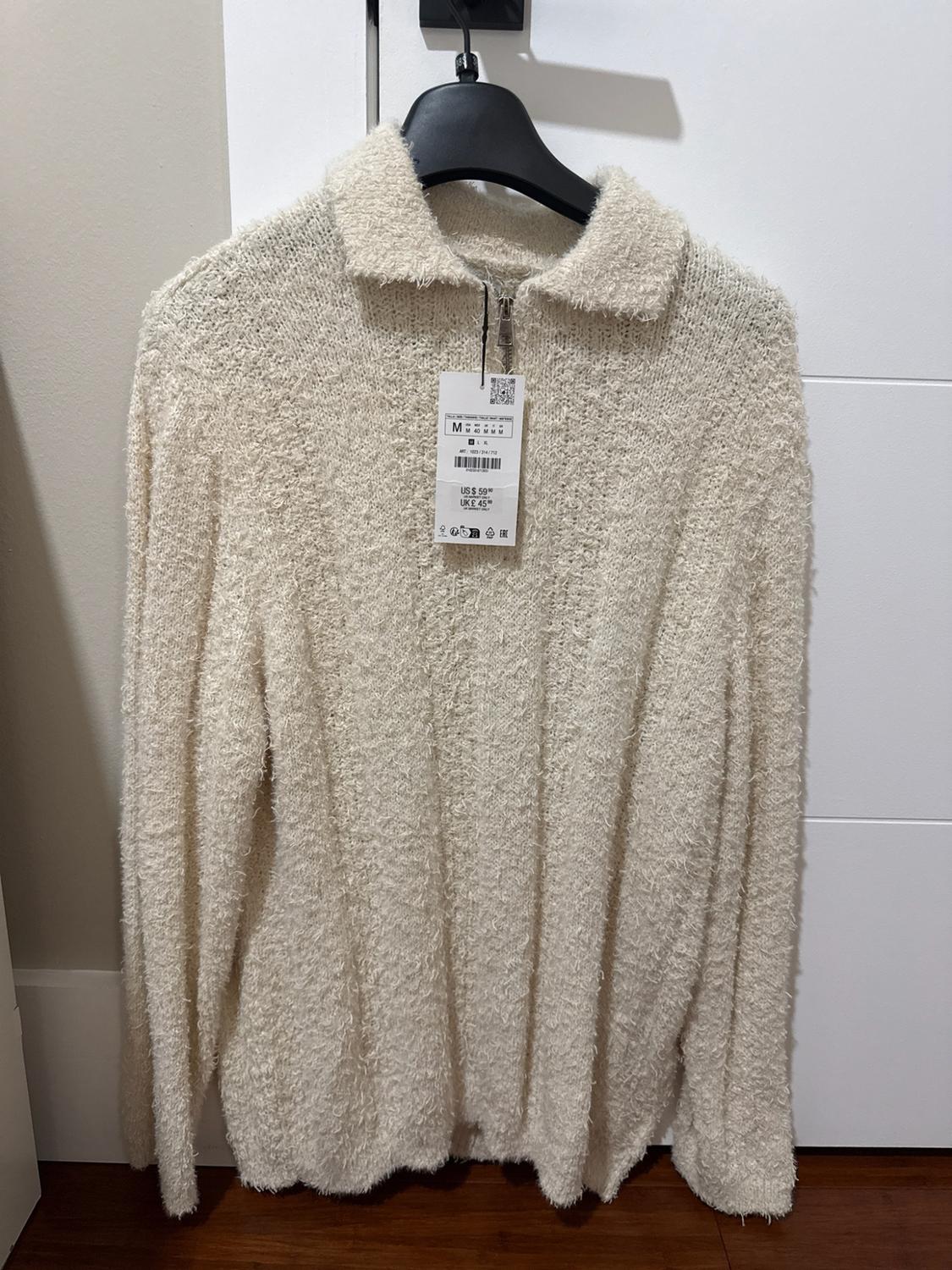 Textured-knit cream sweater with a collar and zipper, hanging on a black hanger. Text on tag: M US $59.90 UK £45.99.