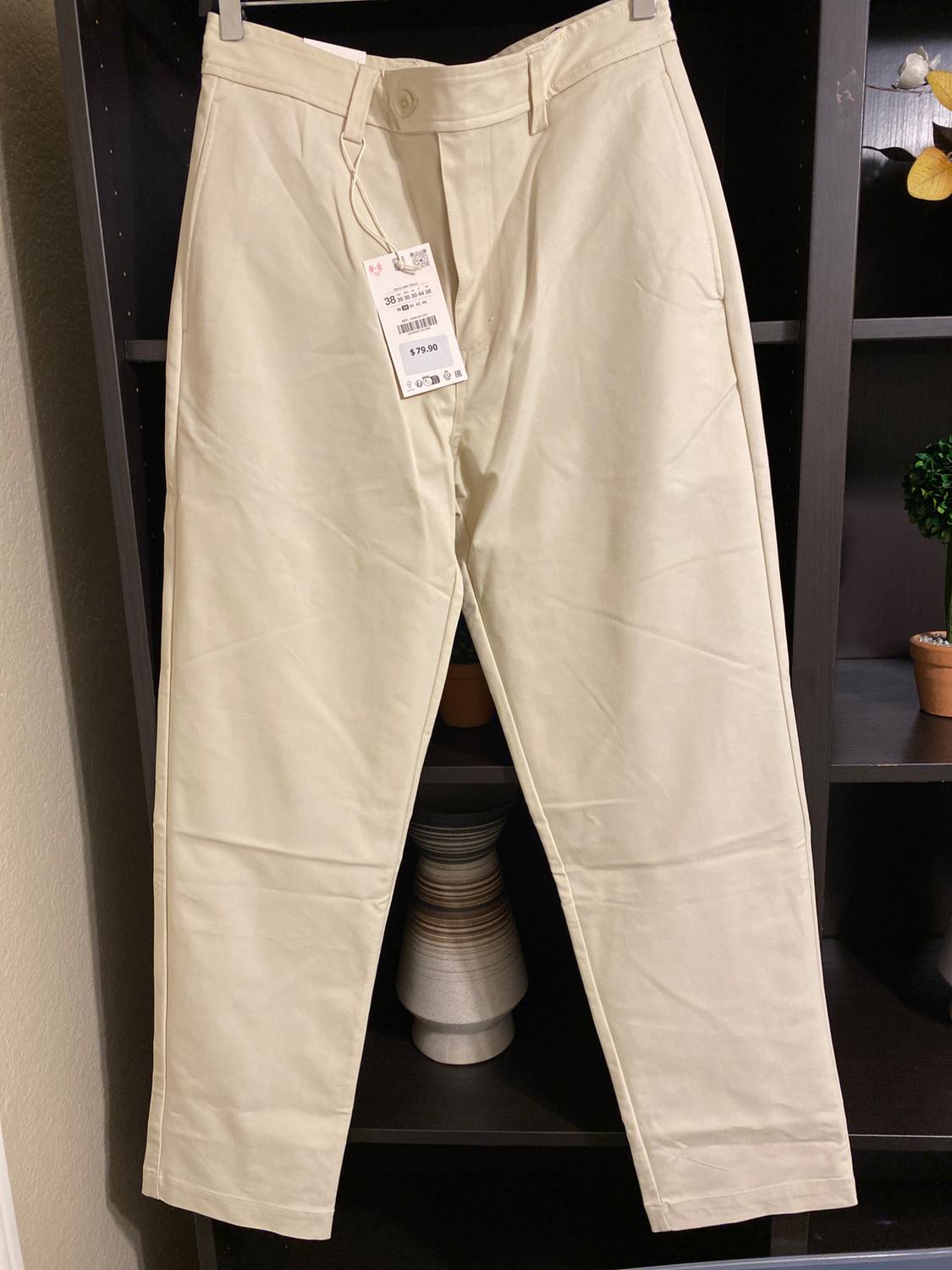 Beige trousers hanging on a dark shelf, with a price tag of $79.90 visible on the front.