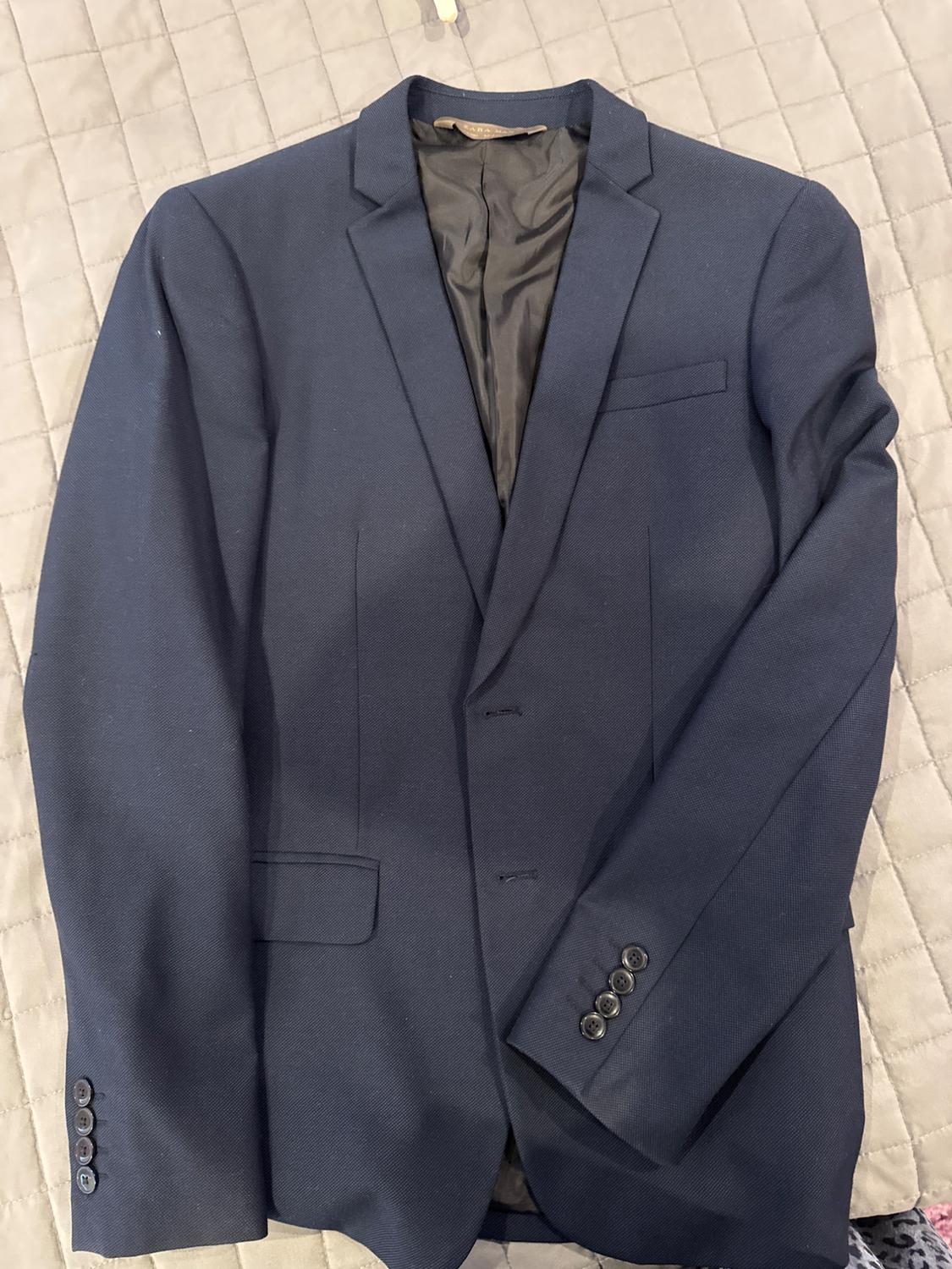 Front view of a navy blue jacket with a lapel, front pockets, and button closure.