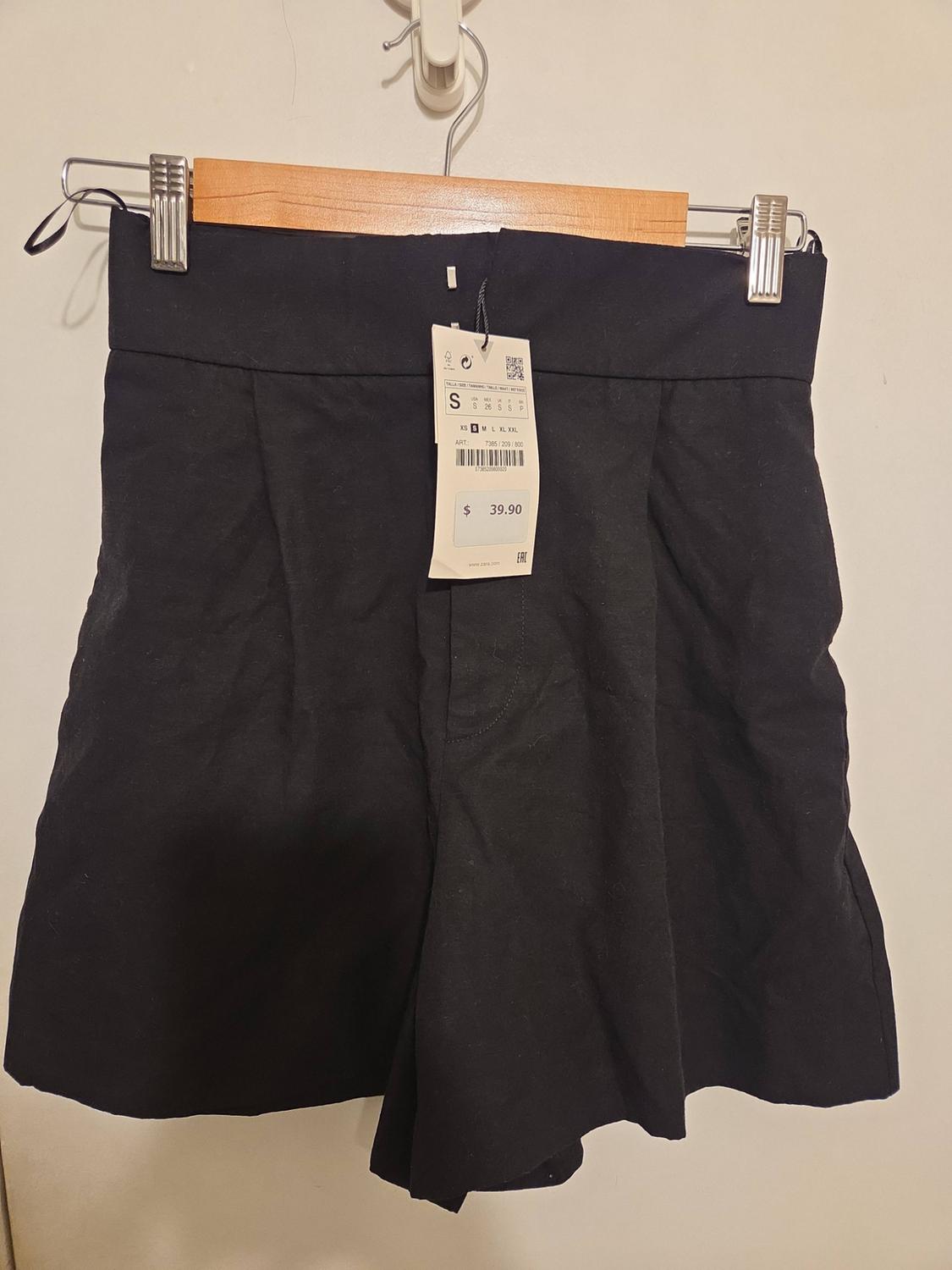 Black pleated shorts on hanger. Text: S XS S M L XL XXL ART: 7385/200/800 $ 39.90 EAC www.zara.com