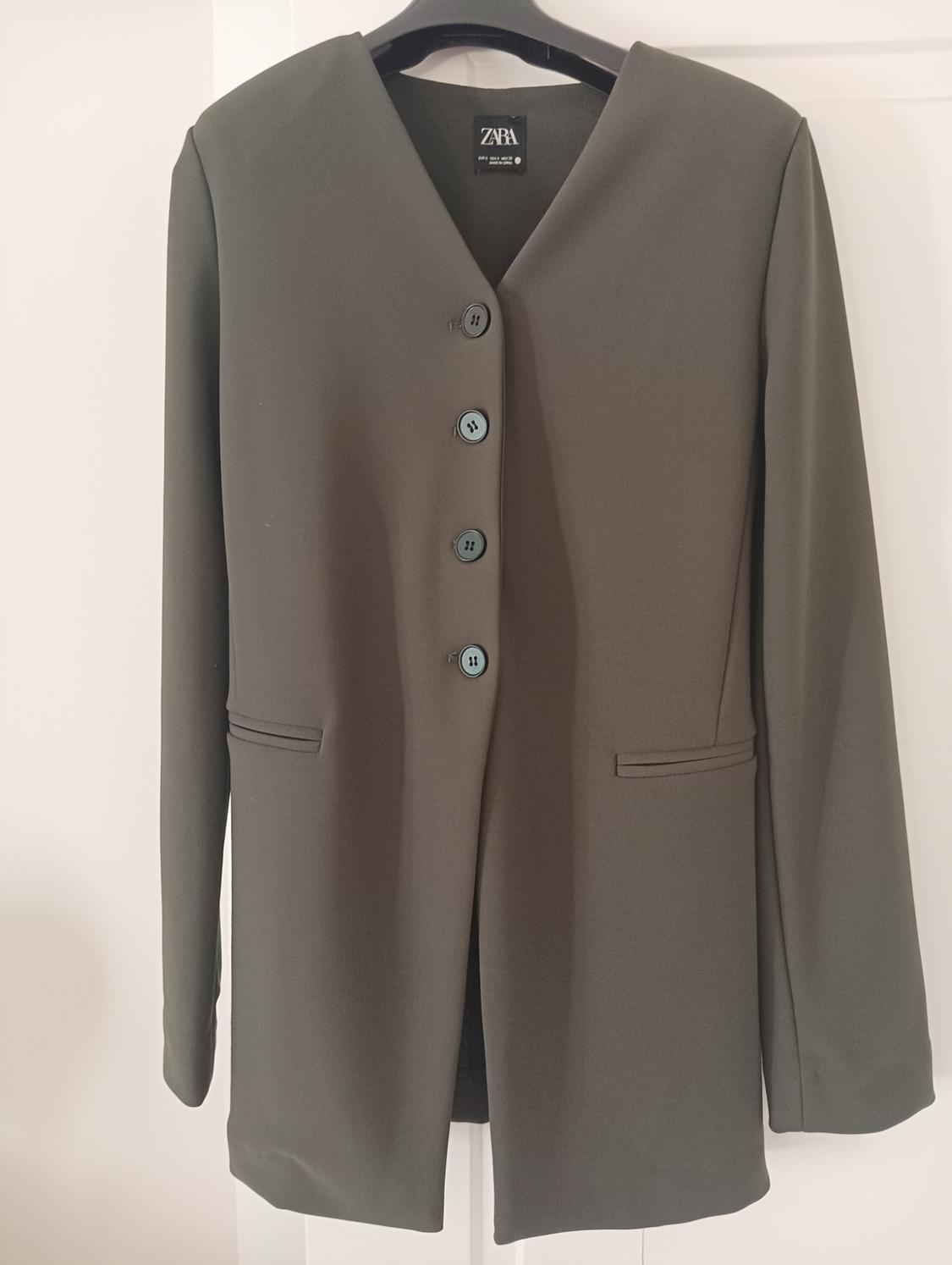 Olive green Zara jacket with front buttons and faux pockets, hanging on a hanger against a white background.